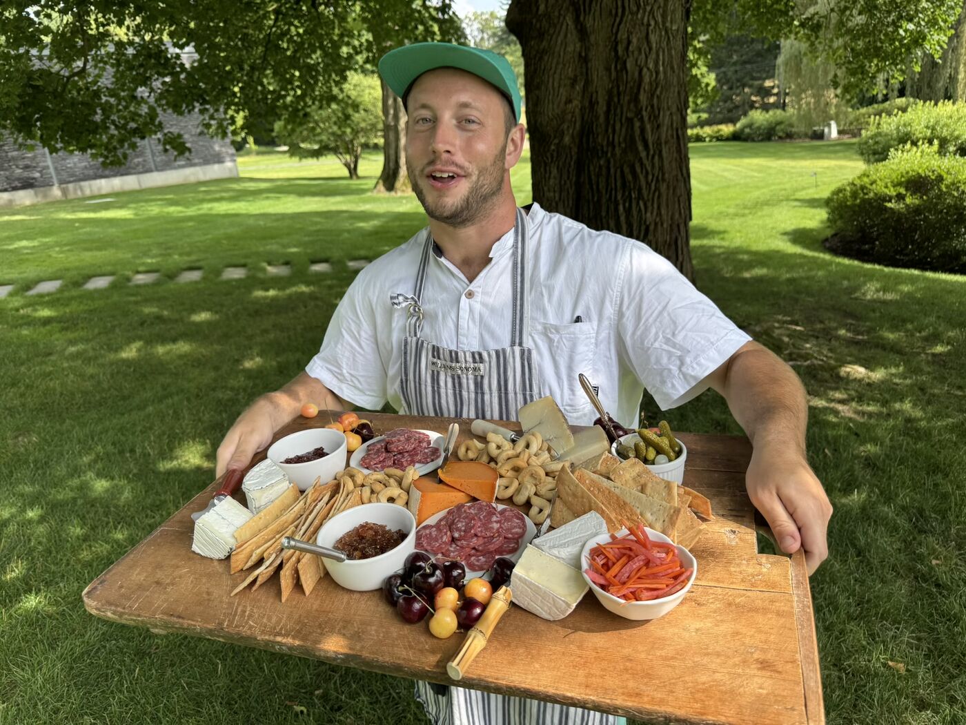 Chef Londrel outdoors with a full charcuterie and pizza spread