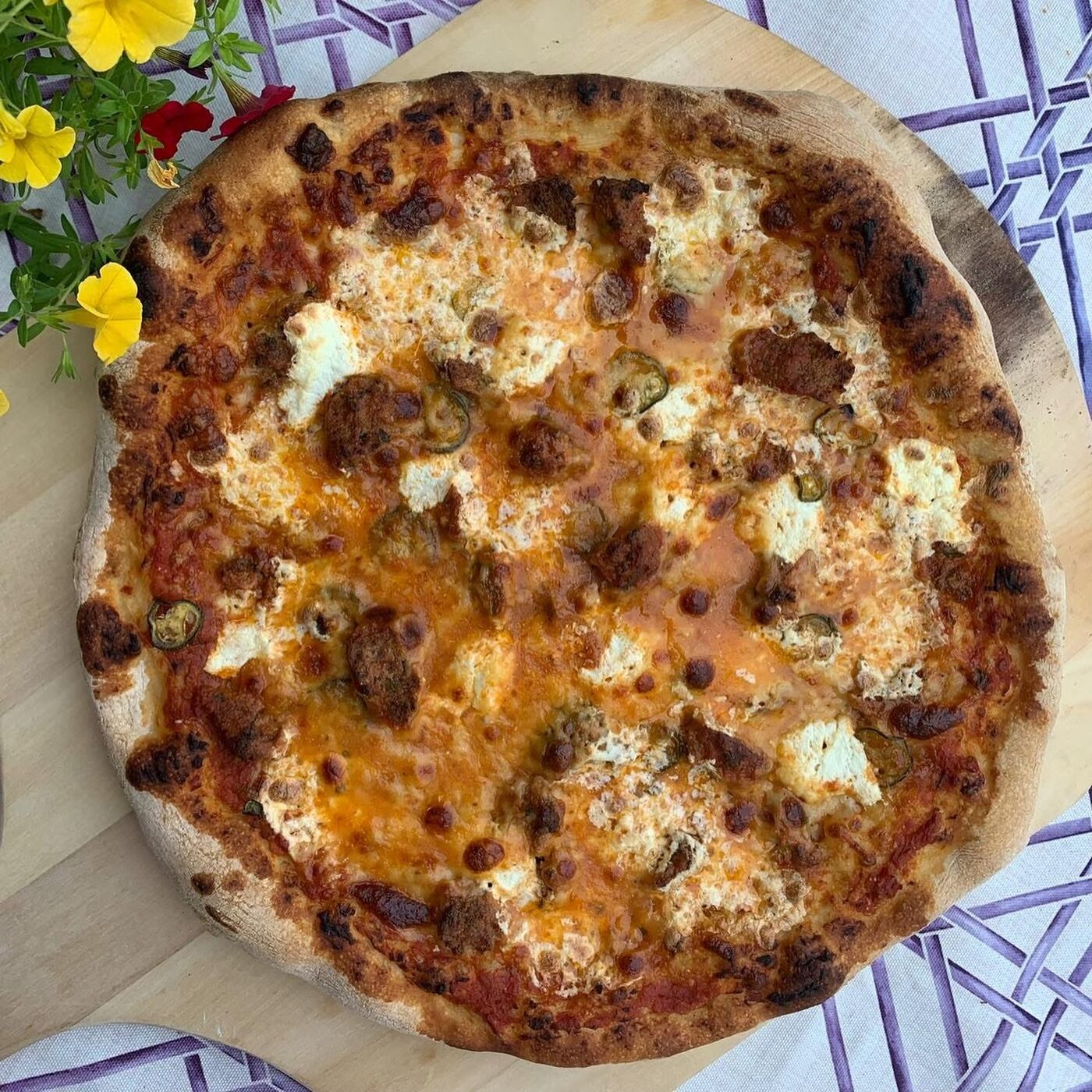 Artisan pizza on checkered cloth with flowers — private chef catering Berkshires